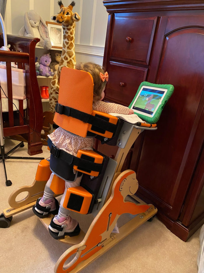 a young girl on a stander, watching coco melon on her ipad